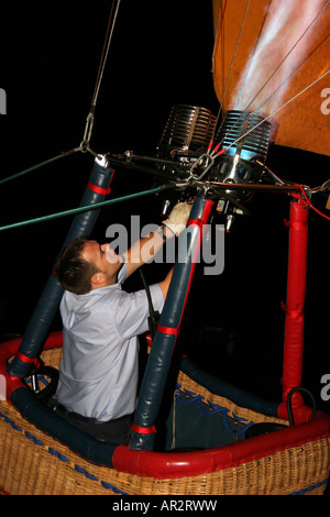 Spettacolare la notte a palloncino Glow close up dettaglio del pilota di accensione del bruciatore in mongolfiera in piedi in un cesto di vimini Foto Stock