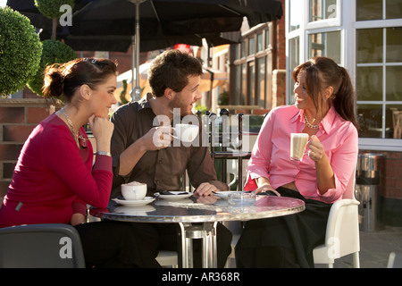 Tre amici due giovani donne e un uomo di bere il caffè e rilassarsi al di fuori di un cafe Hessle vicino a Kingston upon Hull East Yorks Foto Stock