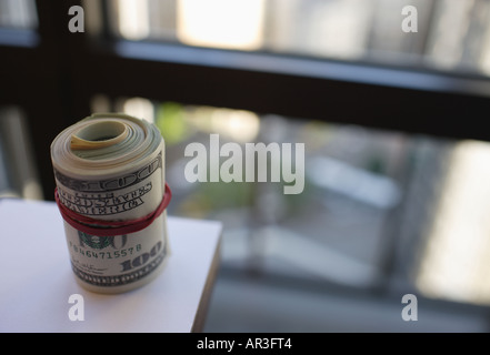Rotolo di dollari americani tenuti insieme con una fascia elastica sul piano executive Foto Stock