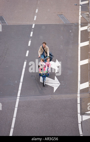 HOLLAND AMSTERDAM MADRE CON DUE BAMBINI su una nave da trasporto bicicletta pedalando su una doppia due frecce bianche segno dipinto sulla strada Foto Stock