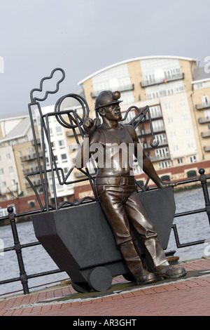 Dalla Fossa alla porta da Giovanni Clinch; Statua in bronzo di Welsh minatore di carbone, Cardiff Docks con nuovo waterside apartments in background Foto Stock