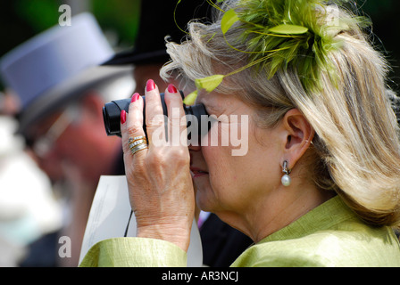 Donna matura guardando attraverso il binocolo, royal ascot, Inghilterra Foto Stock