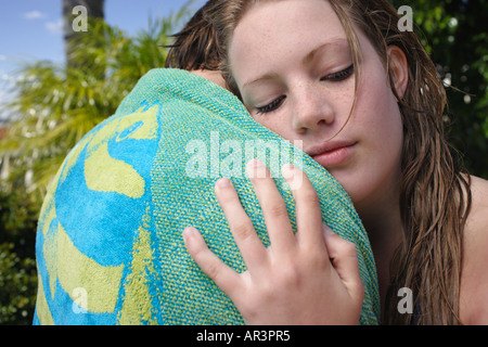 Giovane donna abbracciando giovane avvolto in telo da spiaggia Foto Stock