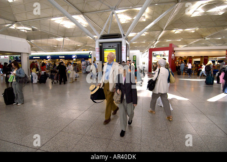 Passeggeri (marito e moglie) all'interno di l'aeroporto di Stansted - Le due principali anziane persone che camminano verso l'uscita in questa immagine sono MRed Foto Stock