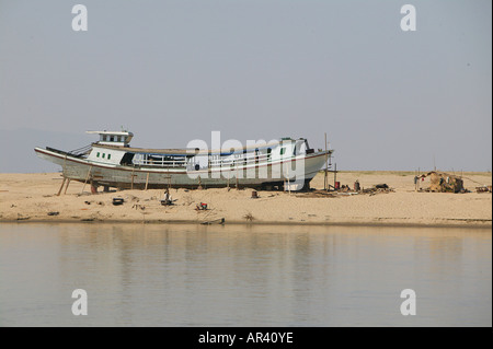 Riverside scenario, in barca nel bacino di carenaggio, fiume Irrawaddy scena vecchia barca essendo riparata in riverbank Boot am Ufer der Ayeyarwady Flus Foto Stock