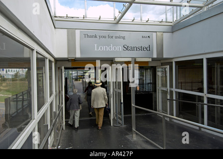 Passeggeri a piedi giù il corridoio al di fuori del Stansted - La coppia di anziani oltre il 3° lady a sinistra di Gent in un cappello sono il Sig. Foto Stock