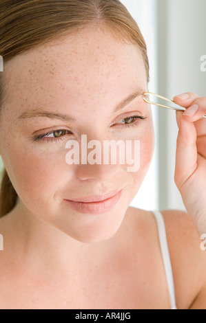 Giovane donna spiumatura sopracciglio Foto Stock