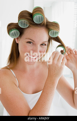 Giovane donna mettendo bigodini nei capelli Foto Stock