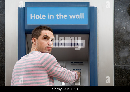 Uomo che guarda sulla spalla al bancomat Foto Stock