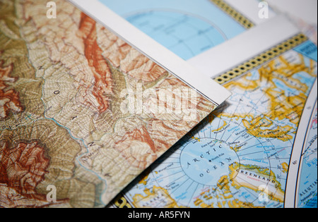 Close-up di mappe stradali che giace al di sopra di ogni altra mappa della zona di montagna e la mappa della zona artica con il polo nord Shallow DOF Foto Stock