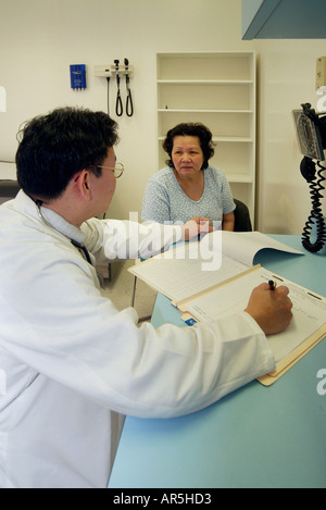 Un medico parla di una mezza età paziente presso una comunità Vietnamese-American clinica medica, Garden Grove, California, Stati Uniti d'America. Foto Stock