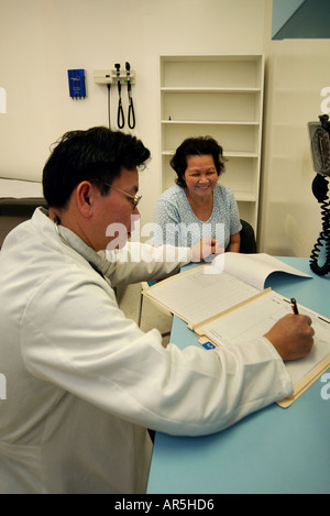 Un medico osserva un informazioni del paziente ad una comunità Vietnamese-American clinica medica, Garden Grove, California, Stati Uniti d'America. Foto Stock