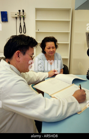 Un medico interviste a persone di mezza età paziente presso una comunità Vietnamese-American clinica medica, Garden Grove, CA modello di rilascio Foto Stock