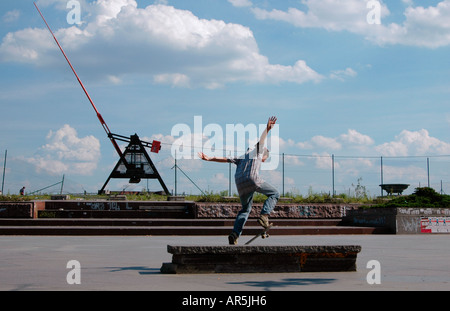 Guidatore di skateboard saltando di fronte al gigantesco metronomo a Letna Park a Praga Repubblica Ceca Foto Stock