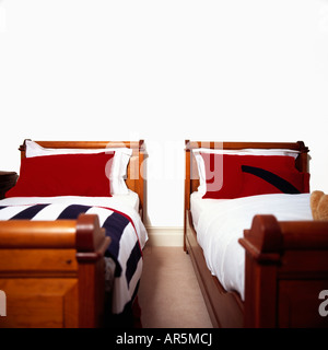 Red i cuscini e le lenzuola bianche sui tradizionali letti singoli nelle moderne camere da letto bianco Foto Stock