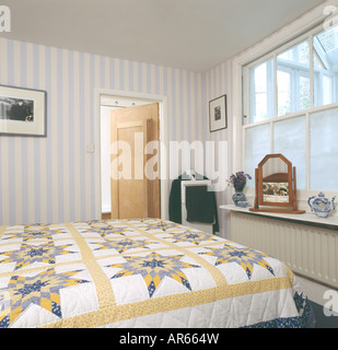 Giallo e Bianco mosaico sul letto in camera da letto casa cittadina di colore grigio con carta da parati a strisce Foto Stock