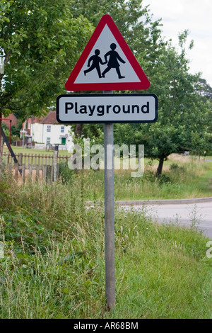 Attenzione il parco giochi per bambini cartello stradale con parco giochi in background Foto Stock