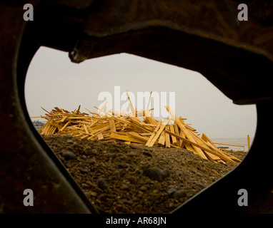 I detriti di legno dal principe di ghiaccio lavato fino a Worthing beach vista attraverso la benna di un escavatore Foto Stock