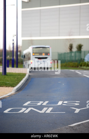 Un colpo di una strada segnata "bus" solo in primo piano con un bus a distanza Foto Stock