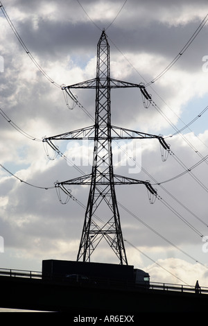 Elettricità pilone con autocarro stagliano contro un cielo scuro Foto Stock