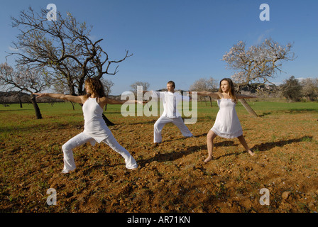 Signor tre persone, uno svedese uomo, una donna brasiliana e una donna spagnola, la pratica dello yoga nei campi di Ibiza, Spagna Foto Stock