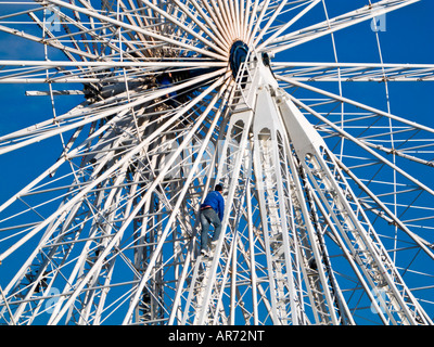 Uomo di manutenzione si arrampica la grande ruota panoramica Ferris in Place de la Concorde Parigi Francia Europa Foto Stock