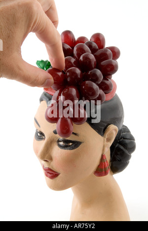 Raccolta a mano un'uva da una Carmen Miranda testa di gesso Foto Stock