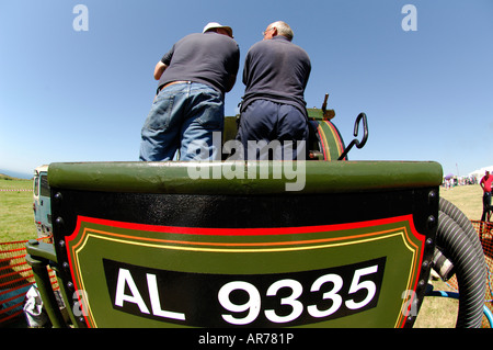 Due gli appassionati di vapore di uomini in abiti da lavoro sorgeva su un grande motore di trazione showmans schiacciasassi presso un paese mostra esposizione Foto Stock