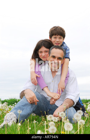 Ritratto di una famiglia felice di tre su erba verde Foto Stock