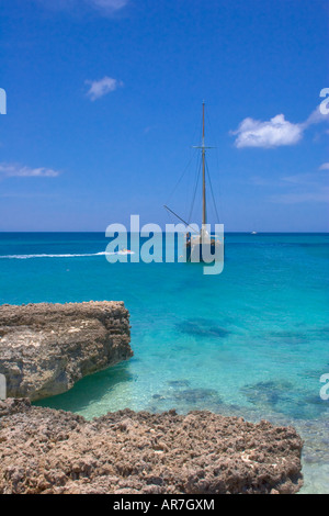 Spiaggia baie isolate da rocce e barca ancorata alla costa ovest di Aruba. Foto Stock