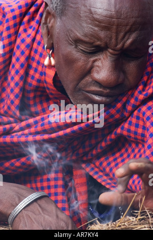 Ritratto di uomo Masai indossando trraditional mantello e decorazioni messa a fuoco con bastoni Foto Stock