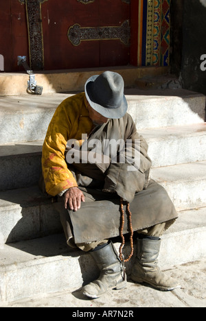 Un esaurito pellegrino tibetano pende la sua testa nel resto, Lhasa il Tibet, della Repubblica popolare cinese Foto Stock