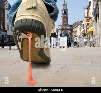 Close up bubble gum bloccato per formatori. Un pedone a piedi lungo una strada viene scartata la gomma bloccato al suo trainer Foto Stock