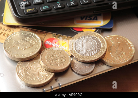 Pila di pound e due libbre di monete e piccolo cambiamento, carte di credito e calcolatrice. Foto Stock
