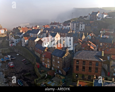 Lo storico villaggio di pescatori di Staithes North Yorkshire con la rottura sole attraverso la nebbia del mare Foto Stock