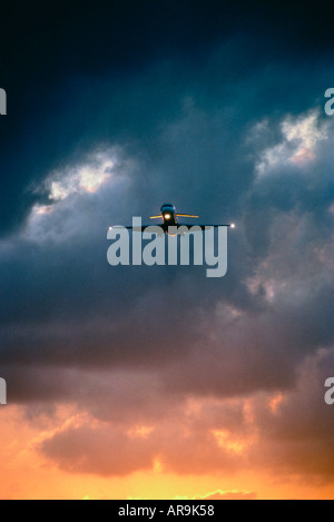 Aereo jet con luci su approccio all'aeroporto in un cielo nuvoloso scuro al tramonto Foto Stock