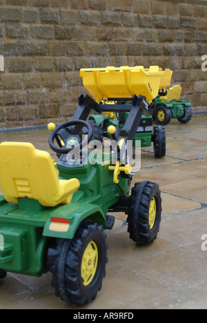 Bambini i trattori giocattolo sul bagnato a Alnwick Gardens Northumberland England Regno Unito Regno Unito Foto Stock