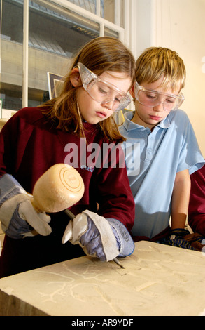 Anno 6 gli allievi della scuola primaria il taglio di lettere in un blocco di pietra arenaria sotto istruzione presso la vecchia libreria Cardiff Wales UK Foto Stock