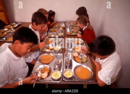 Scuola Cene sana e bilanciata che serve pasti di gruppo multirazziale studenti junior a pranzo in mensa scolastica Foto Stock