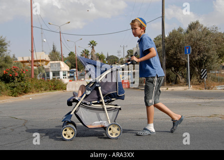 Giovani coloni ebrei di spingere un passeggino nell'insediamento israeliano di Kiryat Arba o Qiryat Arba a Hebron Cisgiordania Israele Foto Stock