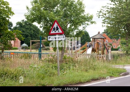 Attenzione il parco giochi per bambini cartello stradale con parco giochi in background Foto Stock