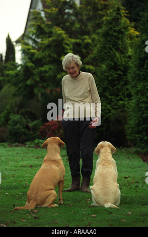 Donna anziana nel suo giardino con due gatti giallo Inghilterra Foto Stock