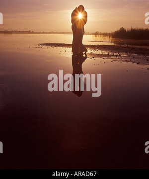 Giovane abbracciando sulla spiaggia al tramonto Foto Stock