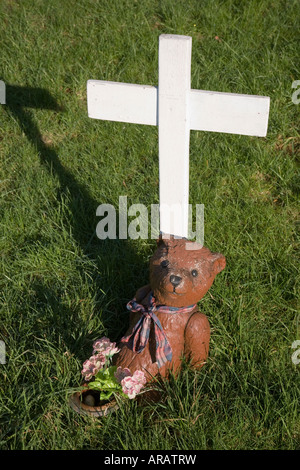 Semplice di legno verniciato di colore bianco e croce orsacchiotto la marcatura di un bambino senza nome la sua tomba in un cimitero Talgarth Wales UK Foto Stock