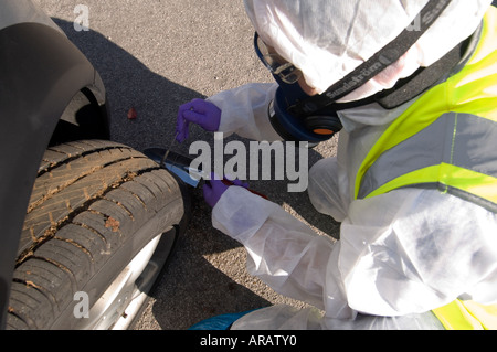 Scena del Crimine officer SOCO raccolta di campioni dal pneumatico e pedali di un veicolo sospetto Foto Stock