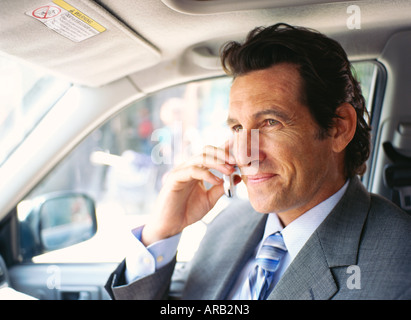 Imprenditore in auto, tramite telefono cellulare Foto Stock