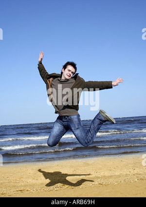 Giovane uomo jumping contro il cielo blu Foto Stock