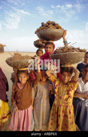 Le donne e i bambini la raccolta del letame per i loro fuochi, nei pressi di Khimsar, Rajasthan, India Foto Stock