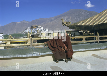 Due monaci buddisti tibetani in corrispondenza di Jokhang Tempio, con il palazzo del Potala dietro, Lhasa, in Tibet, in Cina Asia Foto Stock