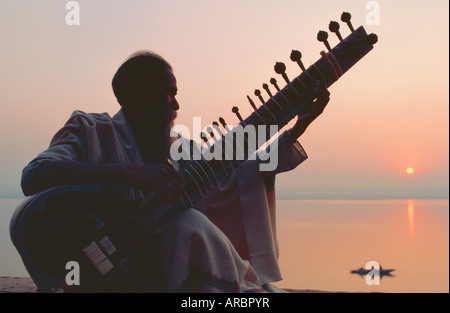 Uomo anziano giocando il sitar accanto al Gange Ganga (Fiume), Varanasi (Benares), nello Stato di Uttar Pradesh, India Foto Stock